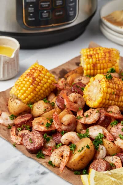 Shrimp boil on a sheet of parchment paper with an Instant Pot in the background.