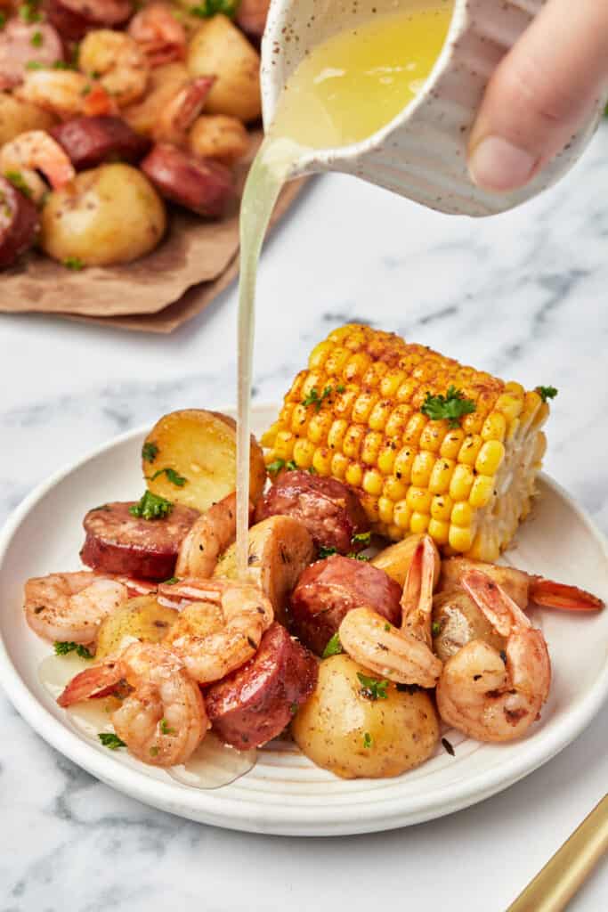 A plate of Instant Pot cajun shrimp boil with butter being drizzled over top.