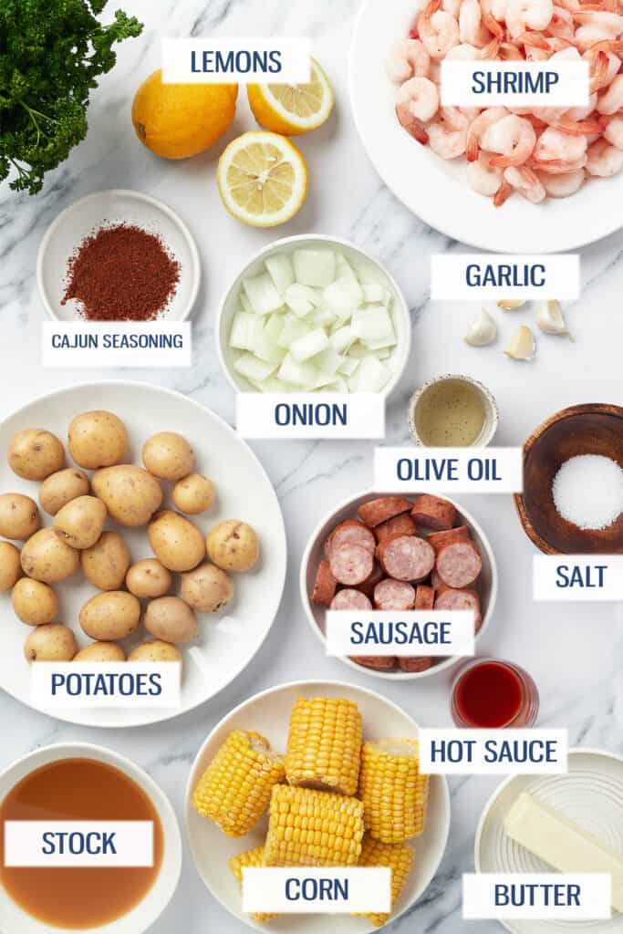 Ingredients for Instant Pot Cajun shrimp boil: lemons, shrimp, Cajun seasoning, onion, garlic, potatoes, sausage, salt, stock, corn, hot sauce, and butter.