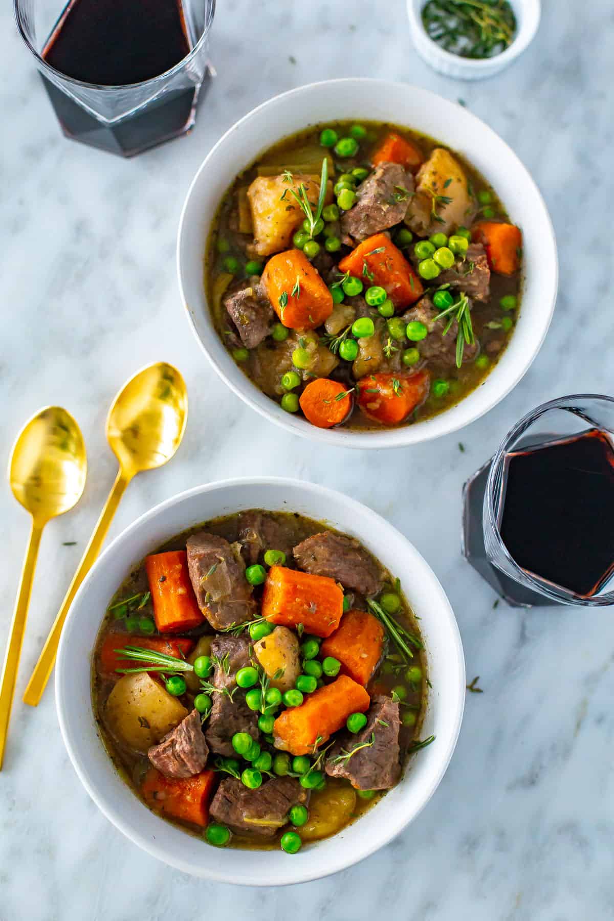 Two bowls on Instant Pot beef stew with glasses of red wine nearby.